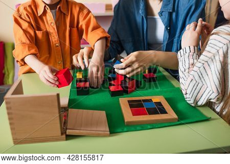 Cropped View Of Children Playing With Multicolored Cubes With Teacher In Montessori School