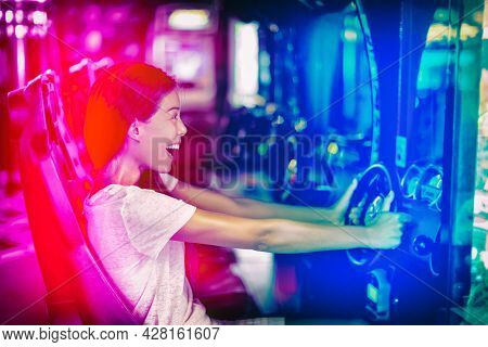Japanese gaming cyber cafe girl gamer having fun gaming. Driving racing car game fun Asian woman playing videogame virtual sports cars arcade machine.