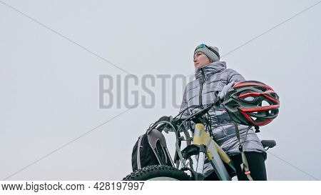 Woman Stands Near Her Bike On Ice. The Girl Cyclist Stopped To R