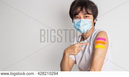 Asian Man Wearing Face Mask With A Smile On His Face Showing His Vaccinated Arm. Fight Against Virus