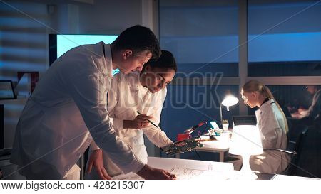 Technology Research Laboratory: Mixed Race Electronics Engineers In White Coats Working With Motherb