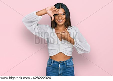 Young latin transsexual transgender woman wearing casual clothes smiling making frame with hands and fingers with happy face. creativity and photography concept. 