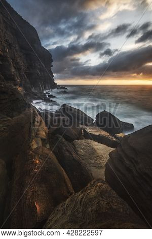 Sunrise On The Rocks In The Middle Of A Body Of Water