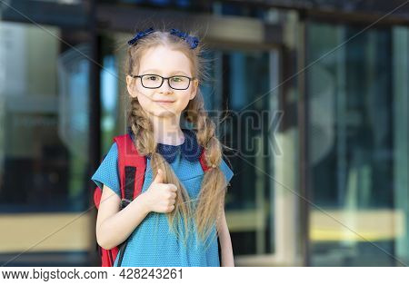 Little Cute Girl In Uniform Dress, Eyeglasses Go To First Grade. Happy Child Back To School, Thumb U