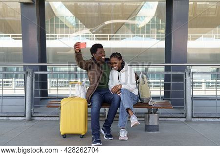 Happy Laughing Couple Of Tourists Taking Selfie Outdoors Airport Terminal Wait For Bus Or Taxi After