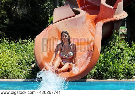 Hisaronu, Turkey - July 2021: Young Woman In Swimsuit Rides A Water Slide At Aqua Park. Summer Vacat