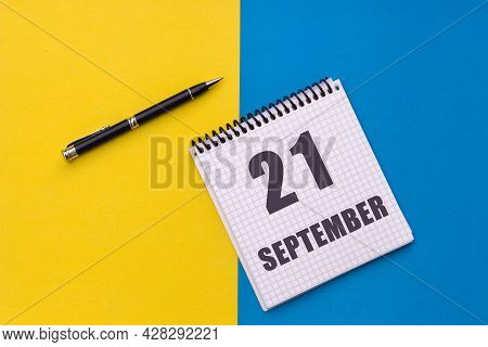 September 21th. Day 21 Of Month, Calendar Date. Notebook With A Spiral And Pen Lies On A Yellow-blue