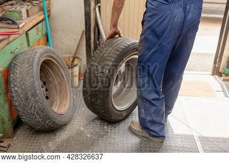 Mechanic Changing Tire In Car Service. Tire Rotation Machine.car Mechanic Mounts Tire On Wheel In A 