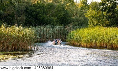 An Image Of A Landscape A Motor Boat Sails On A Reedy River
