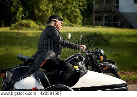 A Handsome Blond Haired, Goatee Wearing Steampunk Biker Driving Black And White Sidecar Motorbike. W