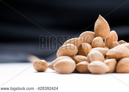 Almonds With Shell, Prunus Amygdalus Heaped On Black Background