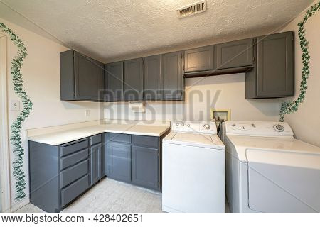 Laundry Room Exterior With Laundry Units And Gray Colored Cabinets And Drawers