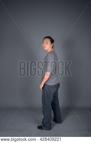 Asian Long Hair Friendly And Positive Man Is Posting And Standing In Front Of Gray Background With S