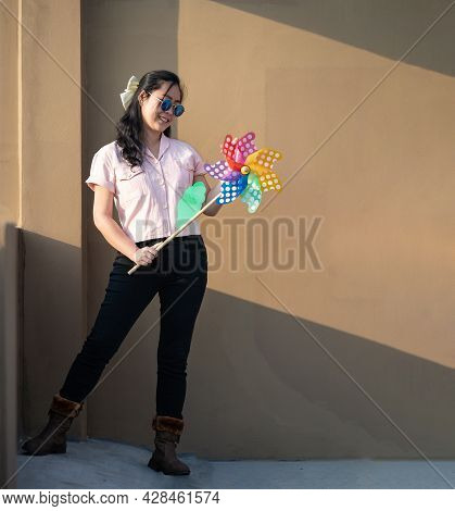 Asian Woman Posts And Play Windmill Toy Colourful Rainbow Colour On The Building Rooftop In Sunset T