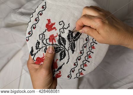 Hands Of The Embroiderer. Female Hands With A Needle, Thread And Thimble. Woman Embroiders Clothes. 