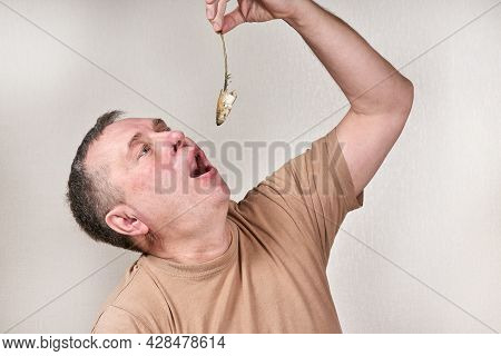 A Man Pulls Out A Smelt Fish Gnawed To The Bone With His Hand