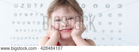 Smiling Little Child Against Vision Test Table In Medical Clinic Portrait