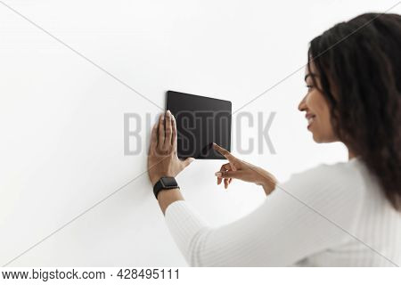 Smart Home. Black Lady Using Thermostat Smart Home Domotic Control Panel On Wall For House Temperatu