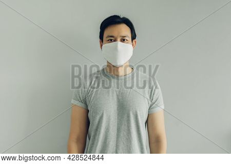 Normal Face Of Asian Man Wearing White Hygienic Mask In Grey T-thirt With Copy Space.