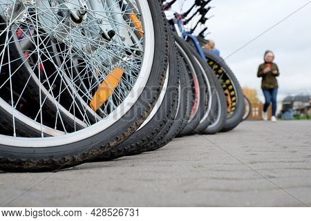 Wheels Of Bcycles Parking For Rent And Abstract Woman On Street Background