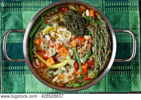 Soupe Au Pistou, French Vegetable Bean Soup With Basil Sauce Pesto And Herbs In A Metal Pot On A Dar