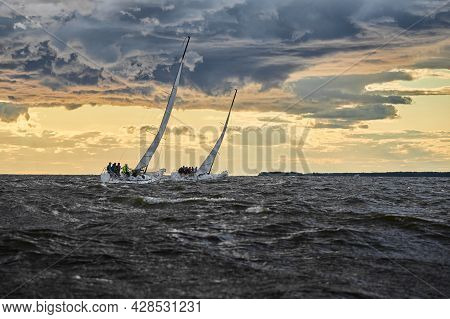 Competition Of Two Sailboats On The Horizon In Sea At Sunset, The Amazing Storm Sky Of Different Col