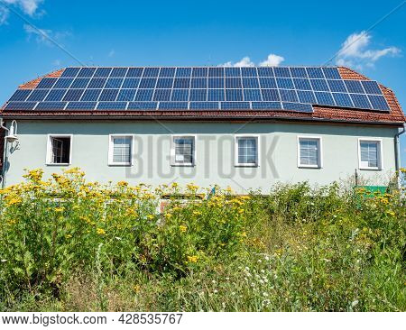 Solar Electric Panels Installed On The Red Tiled Roof Of A House  Europe. Modern Roof  Against The B