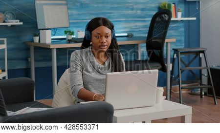 Student Blogger With Dark Skin Putting Headphones Working From Home At Social Media Articole Browsin
