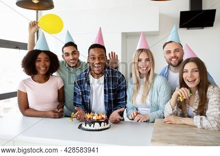 Diverse Young Friends Making Surprise With Cake And Canles For Black Birthday Guy, Throwing Party At
