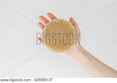 Female Hand Is Holding Hatural Wooden Body Brush In Front Of White Background. Massage, Relax, Spa. 