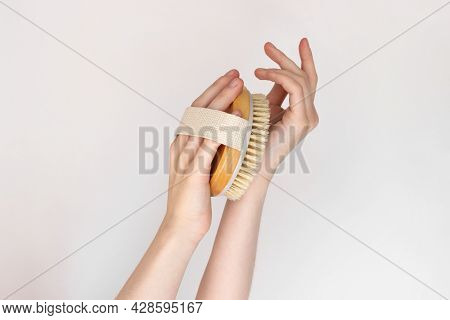 Hand Is Holding Hatural Wooden Body Brush In Front Of White Background. Woman Scrubbing Her Hand. Ma