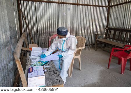 Pithoragarh, India, May, 2021 : A frontline worker in PPE KIT keeping track of RTPCR tests performed