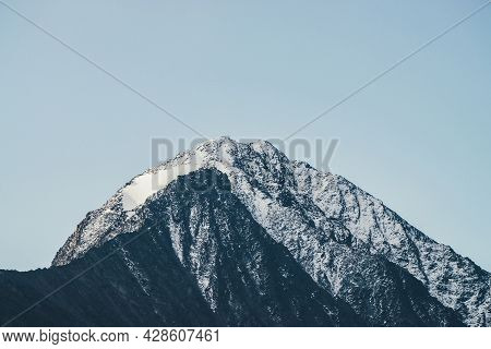 Minimal Mountain Landscape With Black Peaked Top With White Snow Under Blue Sky. Snow-covered Pointy