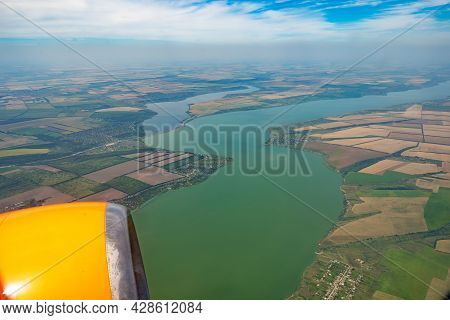 Land View Through The Airplane Window. Fields, Roads, Rivers From A Bird's Eye View. Porthole. Look