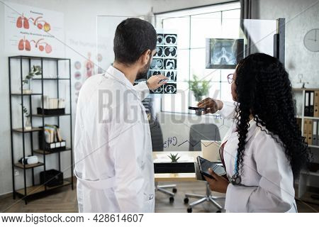 Two Qualified Multiethnic Doctors, Arabian Man And Afro-american Woman, Standing Near The Office Gla