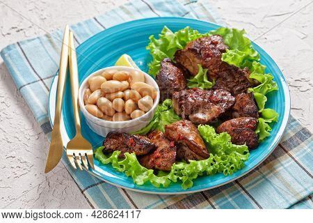Close-up Of Chicken Liver Fry, Kaleji Fry, Served On Lettuce Leaves With Butter Beans And Lemon Wedg
