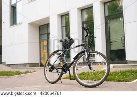 Modern Bicycle Standin On Footplate In City Street On Blurred Background Of Front Door Of Apartment 