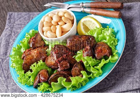 Chicken Liver Fry, Kaleji Fry, Served On Lettuce Leaves With Butter Beans And Lemon Wedges On A Blue