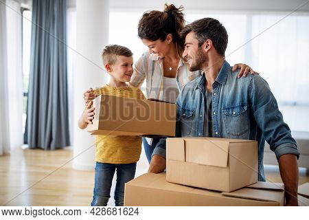 Happy Family Unpacking Boxes In New Home On Moving Day