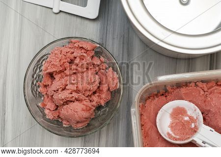Homemade Cherry Ice Cream In A Plastic Container On The Table Next To An Ice Cream Spoon And An Ice 