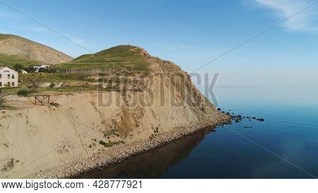 Top View Of Rocky Cape On Background Of Blue Sea. Shot. Remote Life In House On Sea Cape. Beautiful 