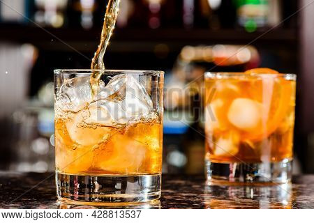 Whiskey Is Poured Into Glass. Glass Of Whiskey On Bar Counter In Restaurant. High Quality Photo