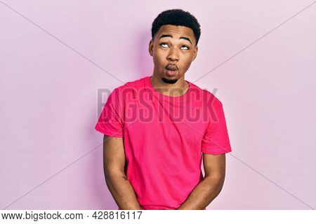 Young african american man wearing casua t shirt making fish face with lips, crazy and comical gesture. funny expression. 