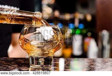 Whiskey Is Poured Into Glass. Glass Of Whiskey On Bar Counter In Restaurant. High Quality Photo