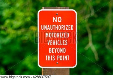 Red Sign With White Letters Attached To A Wooden Post Indicating No Unauthorized Vehicles Beyond Tha