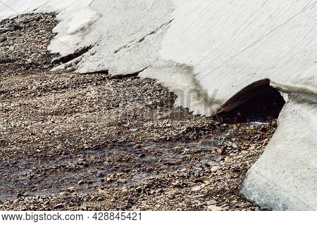 Scenic Alpine Landscape With Small Water Stream Among Stones From Small Ice Cave. Beautiful Mountain