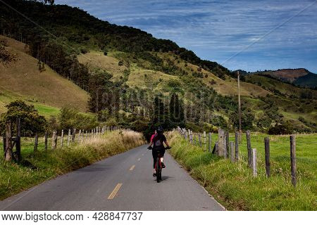 Woman Riding Her Bike On The Beautiful Landscapes Of The Cocora Valley Located At The Quindio Region