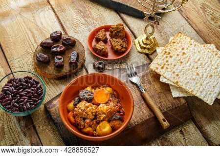 Jewish Dish Chelnt With Meat On A Stand Next To Matzo And Ingredients.