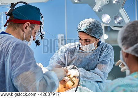 Cosmetic Liposuction Surgery In Actual Operating Room Setting Showing Surgeons Group During Operatio