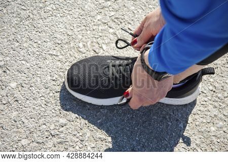 Tying Shoelaces On Black Sneakers. The Girl's Hands Tie The Sneakers